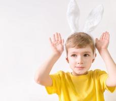 gelukkig kind in een geel t-shirt in konijn oren Aan een wit achtergrond. gelukkig Pasen concept met plaats voor tekst. foto
