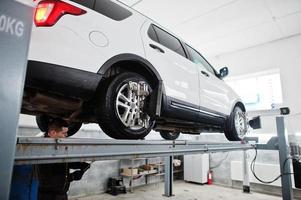 automonteur stelt Amerikaanse SUV-auto in voor diagnostiek en configuratie camber check in werkplaats van tankstation.. foto