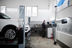 automonteur stelt Amerikaanse SUV-auto in voor diagnostiek en configuratie camber check in werkplaats van tankstation.. foto