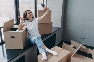 meisje blogger groet volgers in sociaal netwerk, aan het doen Overzicht van nieuw appartement Aan in beweging dag foto