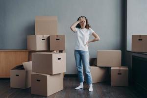 moe van streek vrouw staand met karton dozen in leeg kamer. ontzetting, scheiding, moeilijk in beweging dag foto