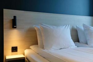 een fragment van een slaapkamer met een modern knus interieur ontwerp van een huis of hotel. zacht hoofdkussen en deken, elegant comfortabel meubilair. foto