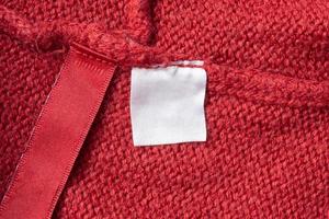 blanco wasserij zorg kleren etiket Aan rood gebreid kleding stof structuur achtergrond foto