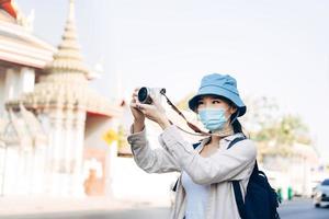 jonge volwassen aziatische vrouw rugzakreiziger draag gezichtsmasker neem een foto met de camera.