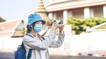 jonge volwassen aziatische vrouw rugzakreiziger draag gezichtsmasker neem een foto met de camera.