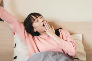 wakker arm stretch Aziatische tiener vrouw in slaapkamer. foto