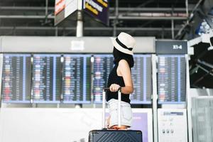 Aziatisch volwassen toerist vrouw met reizen bagage in luchthaven terminal Aan dag foto