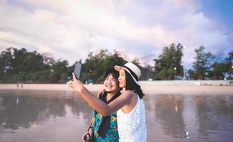 kom tot rust volwassen Aziatisch mensen selfie door mobiel telefoon Bij strand zee. foto