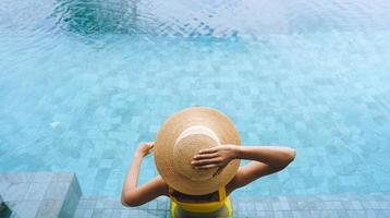 achterzijde en top visie van Aziatisch vrouw kom tot rust Bij zwembad toevlucht reizen Aan zomer vakantie. foto