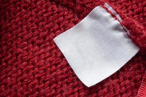 blanco wasserij zorg kleren etiket Aan rood gebreid kleding stof structuur achtergrond foto