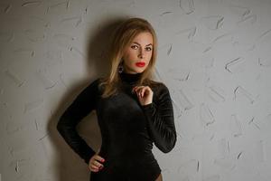 portret van een vrouw in een zwart bodysuit poseren tegen een muur foto
