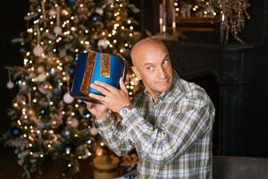 een man met een cadeau bij de kerstboom foto