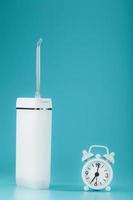 een irrigator voor poetsen uw tanden in de ochtend- en avond met een alarm klok Aan een blauw achtergrond. foto