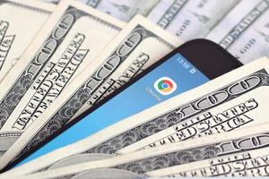 smartphone scherm met google chroom app en veel van honderd dollar rekeningen. bedrijf en sociaal netwerken concept foto