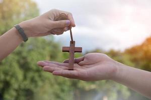 Aziatisch jong christen mensen tonen en geven ketting met een kruis naar andere mensen, zacht en selectief focus, concept voor tonen trots in wezen een christen naar andere mensen in de omgeving van de wereld. foto