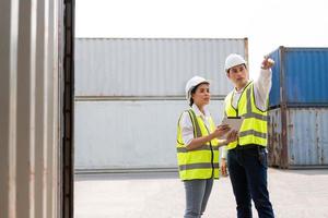 Aziatisch mannen en Dames vracht leidinggevende vervelend veiligheid hesje en hoed terwijl inspecteren staat van allemaal containers Verzending met tablet, mensen en arbeider in vracht leveren, importeren en exporteren. foto