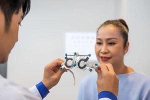 selectief focus Bij Dames gezicht. terwijl dokter gebruik makend van optometrie uitrusting en beproeving bril kader naar onderzoeken oog zichtbaar systeem van ouderling geduldig Dames met professioneel machine en technisch. foto