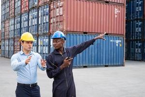 selectief focus Bij Afrikaanse zwart arbeider terwijl praten en hebben discussie met leidinggevende en inspecteren de staat van allemaal containers Verzending, mensen en arbeider in vracht leveren, importeren en exporteren. foto