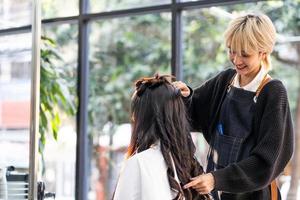 selectief focus Bij gezicht van Dames haar- elegant glimlachen terwijl Doen kappers en zetten zorg behandeling terwijl styling gekruld haar- voor cliënt. professioneel bezigheid, schoonheid en mode onderhoud. foto