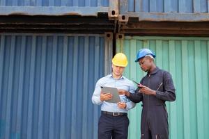 selectief focus Bij Afrikaanse zwart arbeider terwijl praten en hebben discussie met leidinggevende en inspecteren de staat van allemaal containers Verzending, mensen en arbeider in vracht leveren, importeren en exporteren. foto