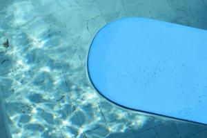 blauw kickboard drijvend Aan zwemmen zwembad water oppervlak. foto