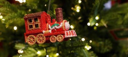 rode speelgoedlocomotief die aan de kerstboom hangt foto