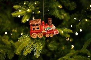 rode speelgoedlocomotief die aan de kerstboom hangt foto