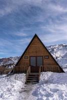 een verticaal schot van een houten huisje omringd door sneeuw. een recreatie Oppervlakte in de bergen foto