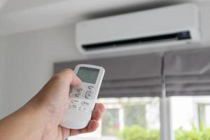 hand met afstandsbediening gericht op airconditioner foto