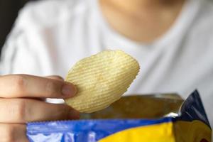 hand- houden aardappel chips met tussendoortje zak foto