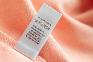 wit wasserij zorg het wassen instructies kleren etiket Aan roze katoen overhemd foto