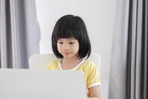 weinig Aziatisch meisje leerling studie online gebruik makend van laptop computer Bij huis foto