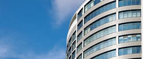 kantoor wolkenkrabber hoog bedrijf gebouw Aan blauw lucht achtergrond, op zoek omhoog naar glas modern gebouw foto