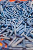 plastic blauwe pluggen op rode achtergrond, muurpluggen voor bevestiging en installatie, close-up, bovenaanzicht foto