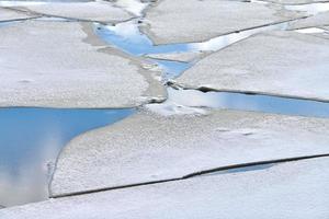 gebarsten ijs van bevroren rivier, blauw water, ijstextuur foto