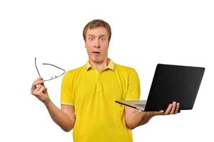 verrast jonge man met laptop en bril in handen geïsoleerd op een witte achtergrond foto