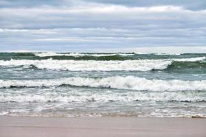 blauw zee, golven, strand en bewolkt lucht. Baltisch zee landschap foto