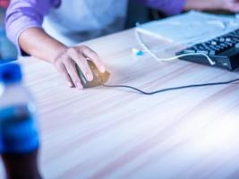 focus omgaan met zwart muis met lang kabel gebruik uw vinger naar controle beide links en Rechtsaf toetsen naar werk. Aan de werk tafel, licht bruin hout korrel. zonder muis stootkussen foto