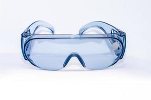 blauw plastic veiligheid bril Aan een wit achtergrond geïsoleerd, dichtbij -omhoog. concept van beroeps Gezondheid en veiligheid foto