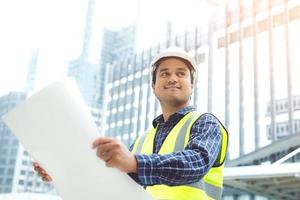 portret van technische aziatische man bouwvakker met rolpapier van tekening structureel plan veiligheid witte helm en draag reflecterende kleding voor de veiligheid van het werk. foto