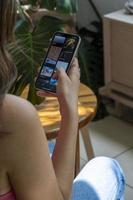 gelukkig millennial spaans tiener meisje controle sociaal media Holding smartphone Bij huis. foto