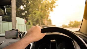 man's hand- Holding stuurinrichting wiel van een zwart auto, wazig achtergrond, oranje licht foto