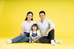 beeld van Aziatisch familie zittend samen gelukkig en geïsoleerd Aan geel achtergrond foto