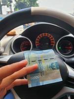 een hand- is Holding een vijftig duizend roepia Bill welke bochten terwijl het rijden. foto