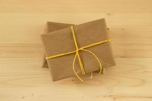 twee geschenk dozen verpakt van ambacht papier en geel lint Aan de houten achtergrond, top visie. foto