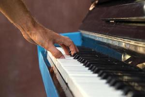 een hand- van een jong Mens spelen piano Aan een straat van stad, detailopname. foto