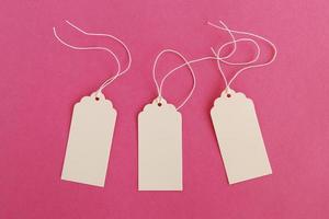 drie wit blanco papier prijs tags of etiketten reeks Aan de roze achtergrond, top visie. foto
