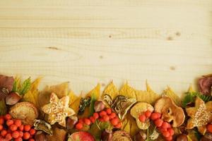 grens van kleurrijk herfst bladeren, paddestoelen, roos heupen, lijsterbes, appels, noten en koekjes Aan de houten achtergrond. vallen achtergrond. foto