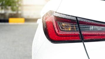 spoor licht van wit auto met laten vallen van water regen. parkeren van asfalt weg parkeren veel Oppervlakte. foto