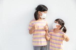 broer of zus weinig meisje vervelend een masker naar hou op coronavirus uitbraak.quarantaine Aziatisch broer of zus.covid-19 coronavirus en pandemisch virus symptomen. foto